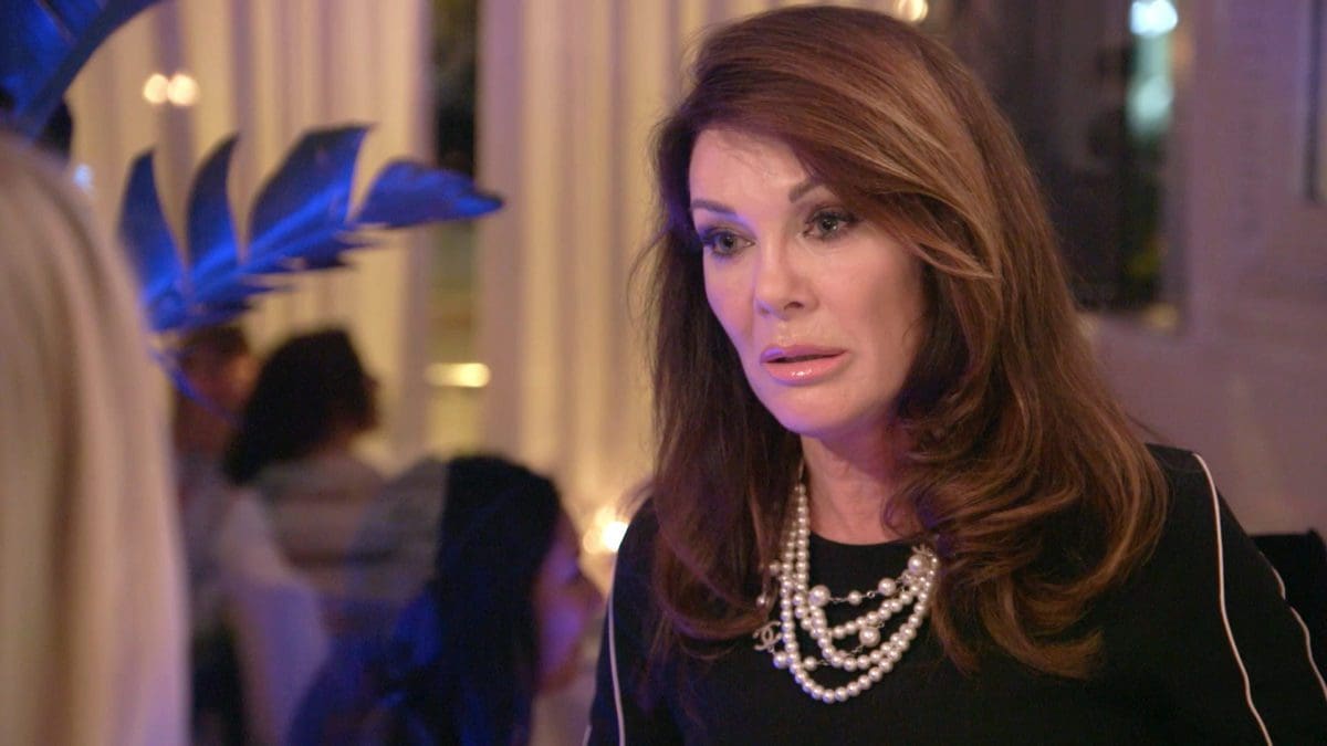 Lisa Vanderpump wearing black top and pearl necklaces looks shocked while discussing drama on Vanderpump Rules